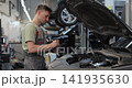 Portrait of a skilled car mechanic in a workshop, with service in the background. 141935630