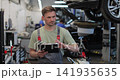 Mechanic man with clipboard walking along workshop. Car service, repair, maintenance and people. 141935635