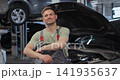 Portrait of a skilled car mechanic in a workshop, with service in the background. 141935637
