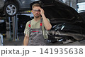 Portrait of a skilled car mechanic in a workshop, with service in the background. 141935638