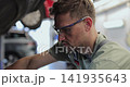 Close up professional mechanic working on a vehicle in a car service. Engine specialist fixing the motor. 141935643