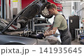 Repairman working on an usual car maintenance. Professional mechanic is working on a car in a car service. 141935645