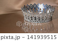 Elegant Gold Crown on Reflective Glass with Sparkling Highlights and Beige Luxury Background. 141939515