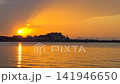 Continuous 4K time lapse of the 2026 partial solar eclipse at golden hour sunset in Spain. Crescent sun emerges from dark clouds and dips behind the silhouette of Denia castle with vibrant orange sea  141946650