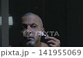 Man shaving facial hair with manual razor in bathroom 141955069