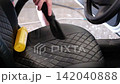 Close-up video of a man's hands vacuuming the front car seats with a handheld vacuum cleaner. No face visible. Car interior cleaning and professional automotive detailing concept. 142040888