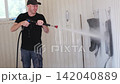 A man washes car floor mats using a high-pressure washer at a professional car wash. A washing and detailing service utilizing a water jet and specialized equipment. 142040889