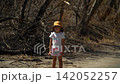 A little girl looks with interest aftermath of a forest fire, trees without leaves and branches, dead wood, asks and inquires about the reasons, turns her head, a sunny spring day. 142052257