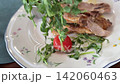 Tender Roasted Duck Served with Fresh Microgreens and Cherry Tomatoes on a White Restaurant Plate 142060463