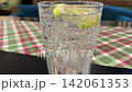 Sparkling Water Poured Over Ice and Fresh Lemon in a Glass on a Colorful Traditional Tablecloth 142061353