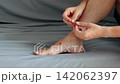 Person applies a protective adhesive bandage to a small red skin wound on the top of the foot 142062397