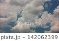 White puffy clouds drifting across a bright blue sky during a sunny afternoon capturing nature in motion 142062399
