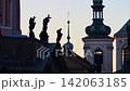 Silhouetted baroque statues on a church gable with a green onion-domed bell tower behind at dawn. Zoom out effect. Prague, Czech Republic 142063185