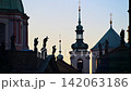 Silhouetted baroque rooftop statues and green church spires against the dawn sky, Prague, Czech Republic 142063186