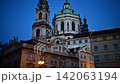 The baroque dome and clock tower of St. Nicholas Church above Lesser Town rooftops at blue hour, Prague, Czech Republic 142063194