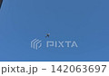 Airplane ascends into a clear blue sky above a building, illustrating the flight path and altitude in a vibrant urban setting 142063697