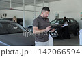 Car salesman signing documents at a dealership 142066594