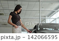 Beautiful woman choosing new car at dealership showroom 142066595