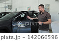 Professional car salesman presenting a new vehicle 142066596