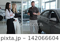 Professional car salesman presenting vehicle to two women 142066604