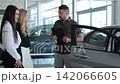 Car salesman explaining features to two female customers 142066605