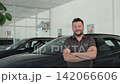Confident car salesman smiling in a dealership showroom 142066606