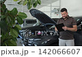 Professional car mechanic checking vehicle report at service center 142066607