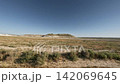 Off-road vehicle speeds across rugged terrain in expansive desert landscape 142069645