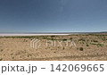 Off-road vehicle speeds across arid landscape with salt flats in background 142069665