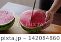 A man cutting a watermelon 142084860