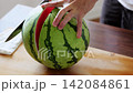 A man cutting a watermelon 142084861