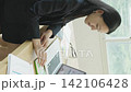 A young Japanese businesswoman operating a calculator by a bright window (vertical video) 142106428