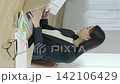 A young Japanese businesswoman working on her computer by a bright window (vertical video) 142106429
