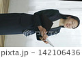 A young Japanese businesswoman smiles by a window, holding a file (vertical video). 142106436