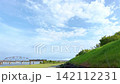 川沿いの土手と広い空の下に走るローカル列車 142112231