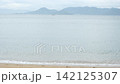 A tranquil sandy beach with gentle waves lapping against the shore and distant islands. 142125307