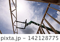 Construction workers raise wooden frames at building site equipment is present for lifting materials. 142128775