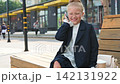 A little girl dressed in a business suit is talking animatedly on a smartphone 142131922
