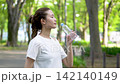 Woman rehydrating in a park outdoors Woman rehydrating in a park outdoors 142140149