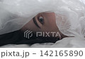 Body beauty and fashion advertisement. Close up of woman's face and eyes partially covered by translucent oilcloth 142165890