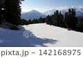 Pov skiing down perfectly groomed slope surrounded by pine forest with majestic snow covered mountain peaks on beautiful sunny winter day in ski resort. Skiing on piste at winter 142168975