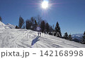 Active woman skiing down groomed slope at mountain resort on sunny winter day with clear blue sky. Skier enjoying alpine vacation and demonstrating her skills. Skier raised arms to happy 142168998