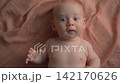 Baby moving arms and legs on cloth and sneezing. Close-up. 142170626