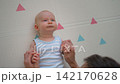 Baby holding father's thumbs with tiny hands. Close-up. 142170628