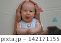 Father gently stroking baby son's head on soft mat. Close-up. Slow motion. 142171155