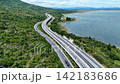 Aerial view of highway running along river and green hills. Transportation, infrastructure, travel and logistics concept 142183686