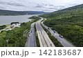 Aerial view of highway running along river and green hills. Transportation, infrastructure, travel and logistics concept 142183687