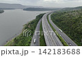 Aerial view of highway running along river and green hills. Transportation, infrastructure, travel and logistics concept 142183688