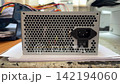 Computer power supply unit with ventilation grille and switch on workbench. Electronics repair, spare parts, hardware maintenance, workshop service. 142194060