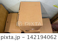 Brown cardboard boxes stacked in corner near white wall for storage or moving. Relocation day, packing things, warehouse clutter, old packaging. 142194062